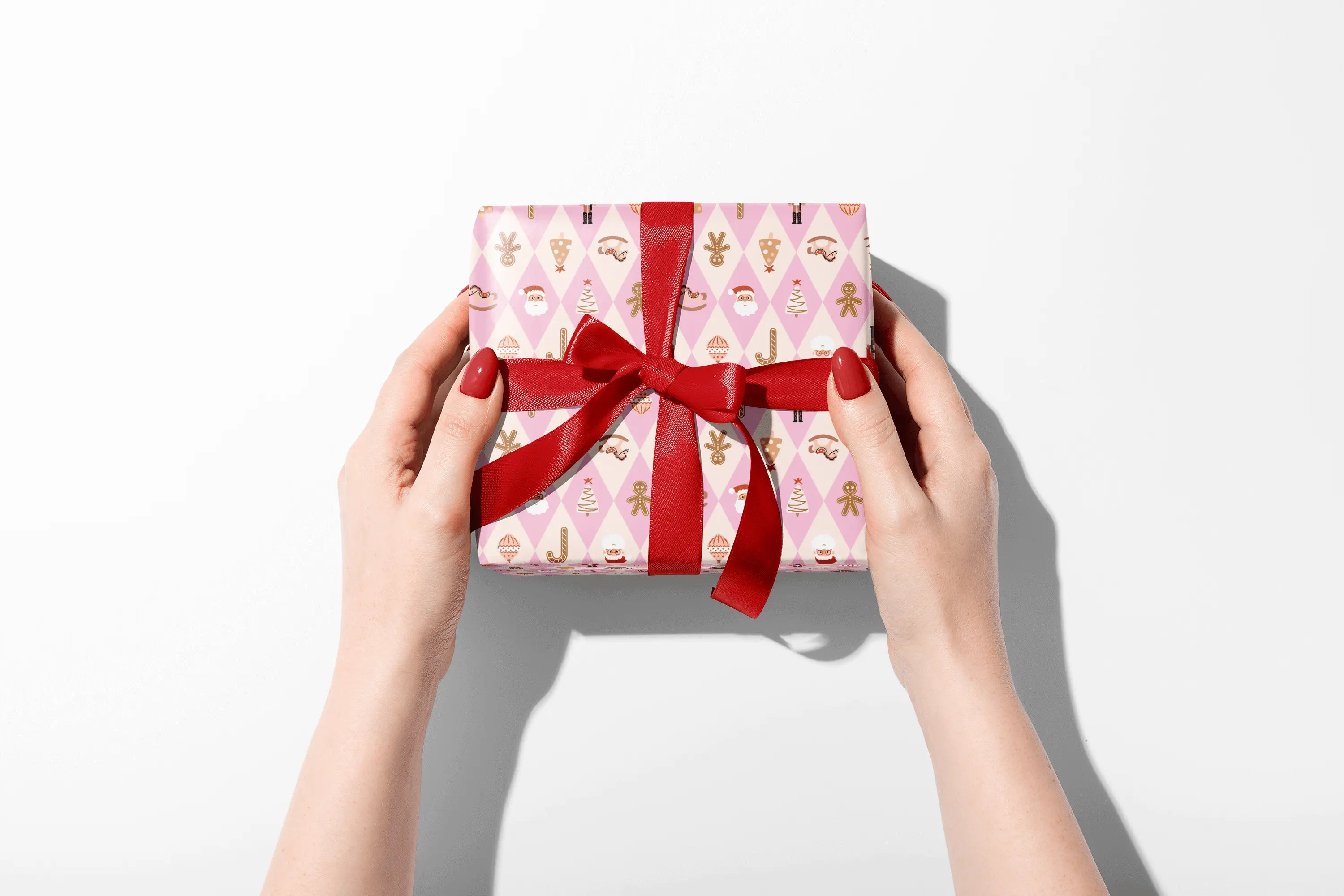 Hands with red nails hold a Haus of Wrap Sugar Plum Diamond gift box, in chic pink wrapping paper—perfect for birthdays or holidays.