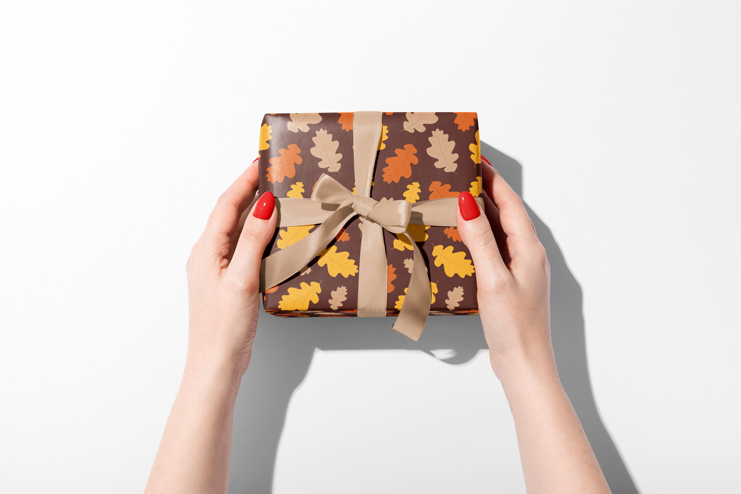 Dense fall wrapping paper with a scattered pattern of stylized leaves in burnt orange, brown, and yellow, ideal for autumn and Thanksgiving gifts.
