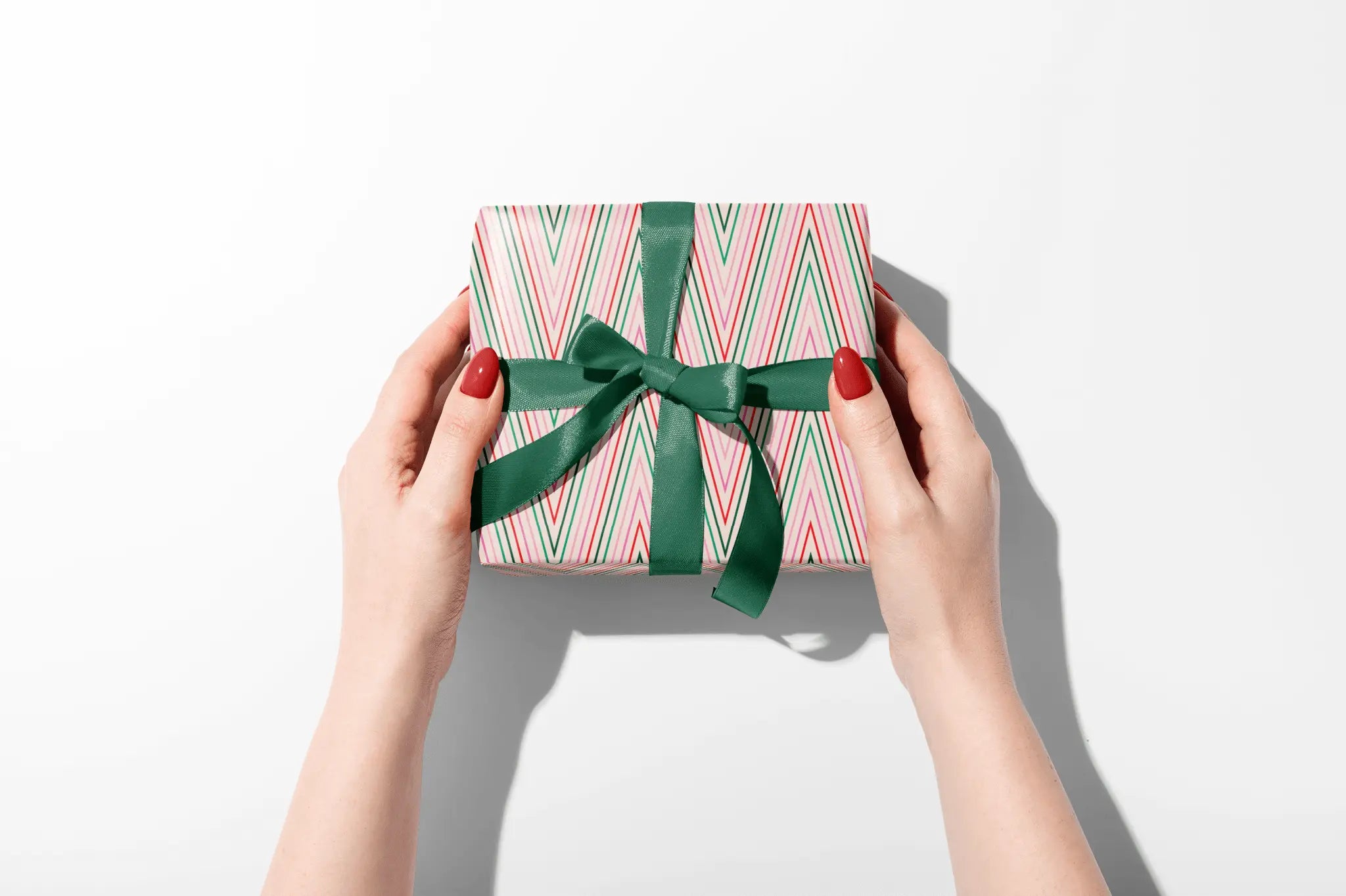 Haus of Wrap chevron gift wrap with green ribbon, perfect for birthdays, weddings, or holidays—held by hands with red nails.