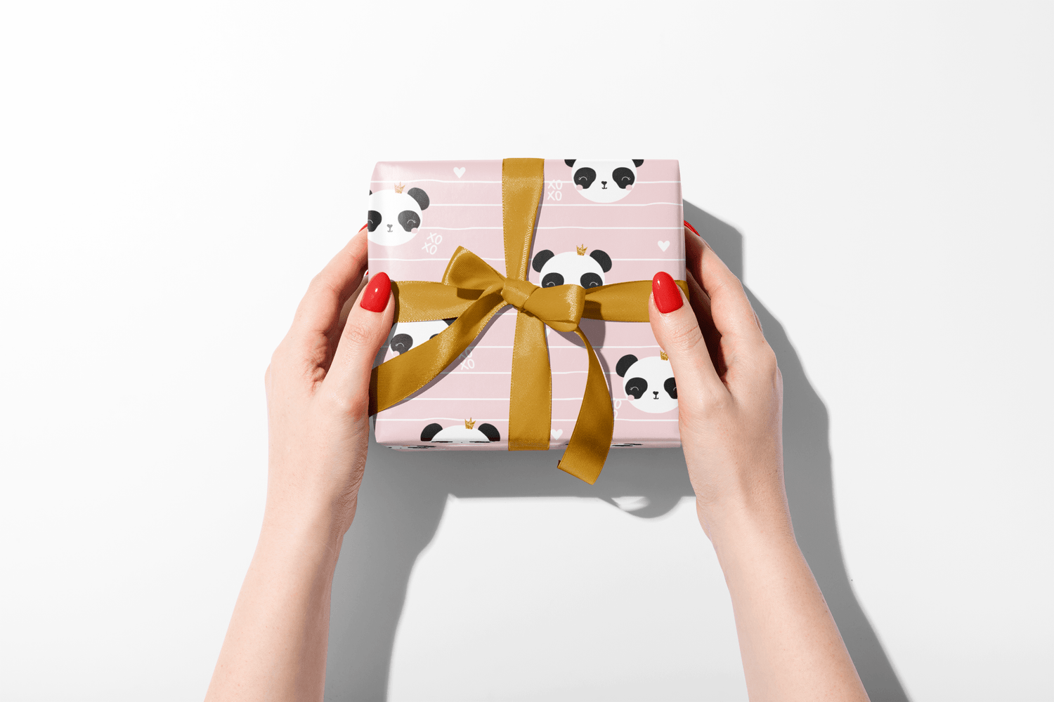 Gift box with panda design and gold ribbon held by hands on a white background