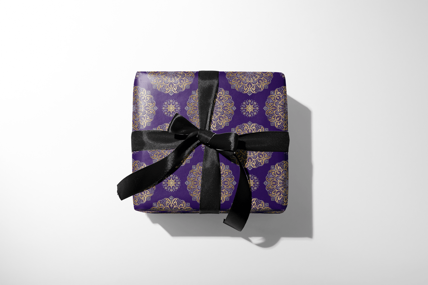 Gift box with purple patterned wrap and black ribbon on a white background