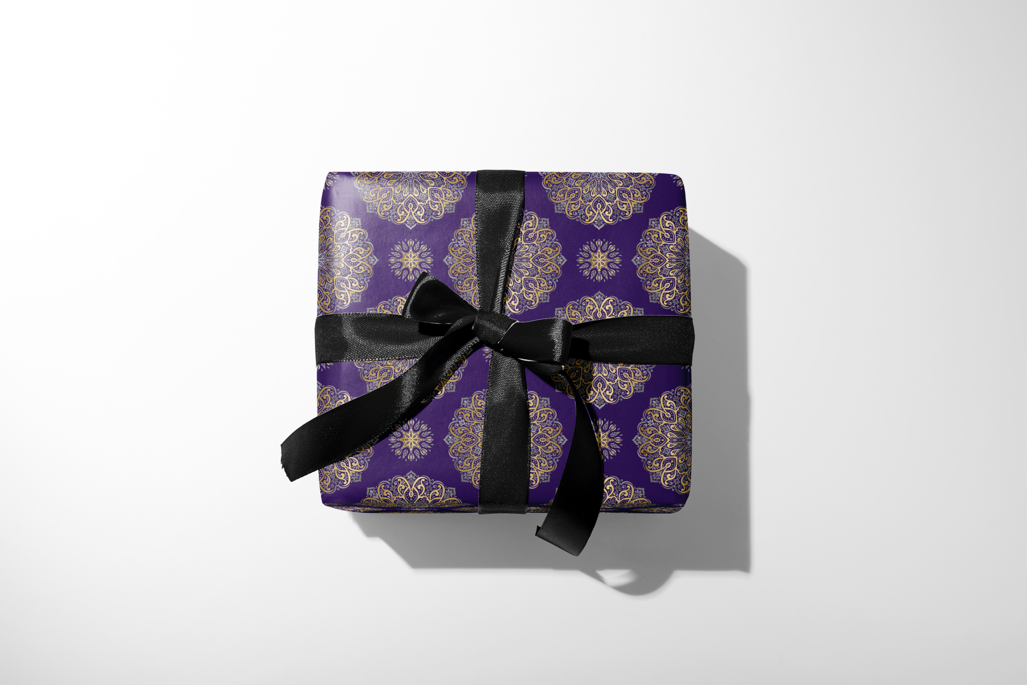 Gift box with purple patterned wrap and black ribbon on a white background