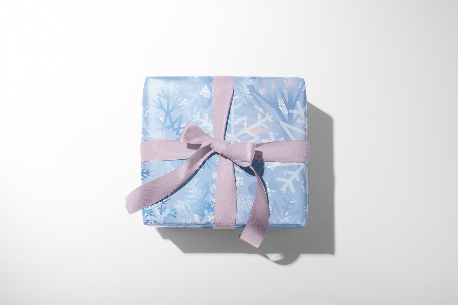 Christmas wrapping paper with an artistic, multi-layered pattern of watercolor snowflakes in shades of blue, lavender, and white, ideal for winter wonderland themes.