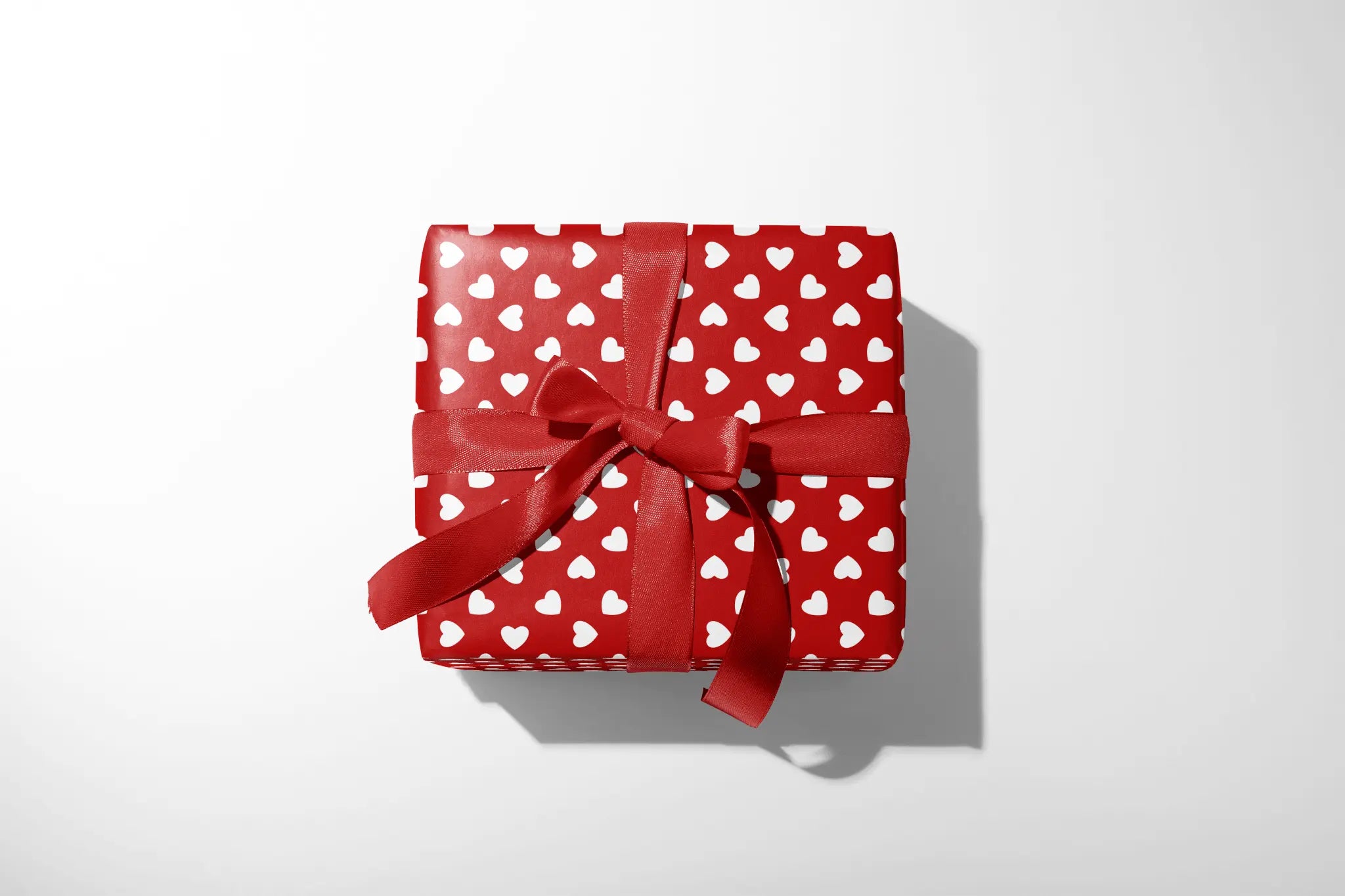 Alt Tag: Classic Red Heart Valentine Wrapping Paper Petit Coeur gift wrap with white heart pattern and red ribbon bow on present