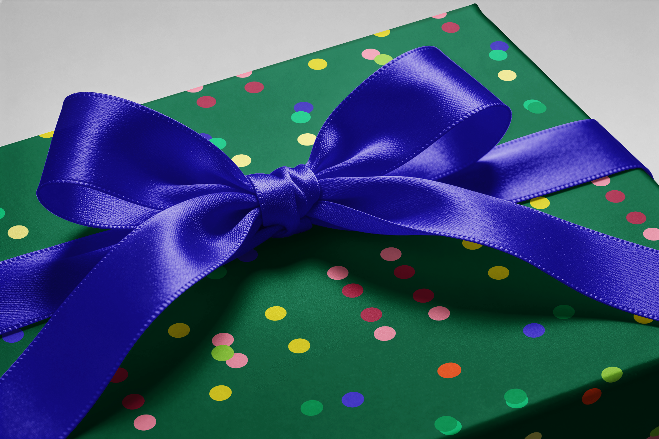 Alt Tag: Confetti Wrapping Paper in Emerald Jubilee design, emerald green with multicolor dots and a royal blue satin bow