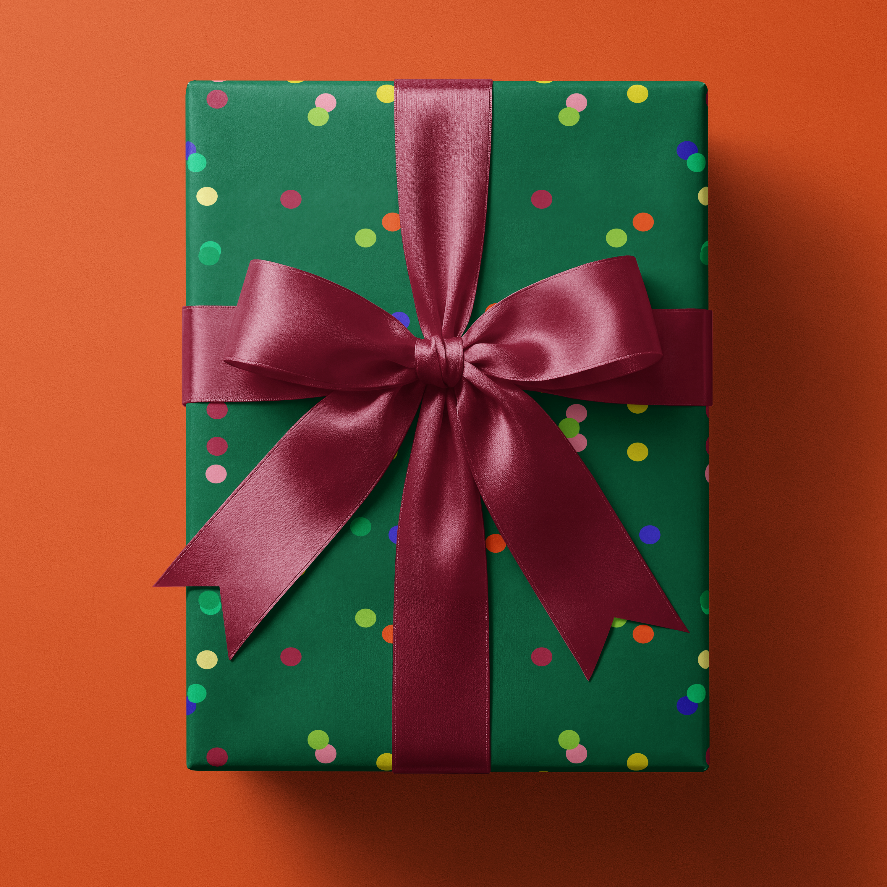 Confetti Wrapping Paper Emerald Jubilee in rich emerald green with multicolor dot confetti pattern, wrapped gift with burgundy satin ribbon