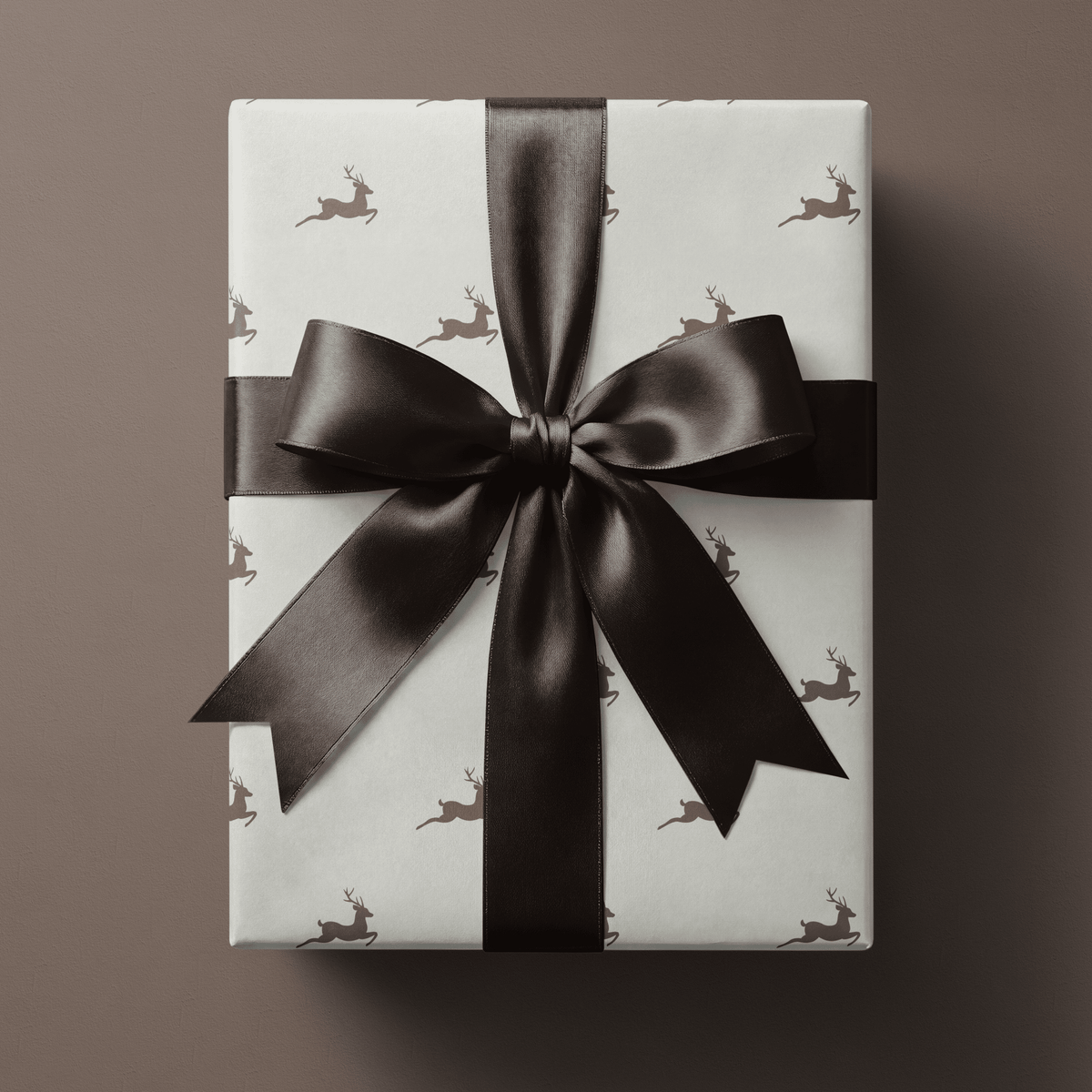 Neutral Christmas wrapping paper with leaping taupe stags spaced evenly across a cream ground.