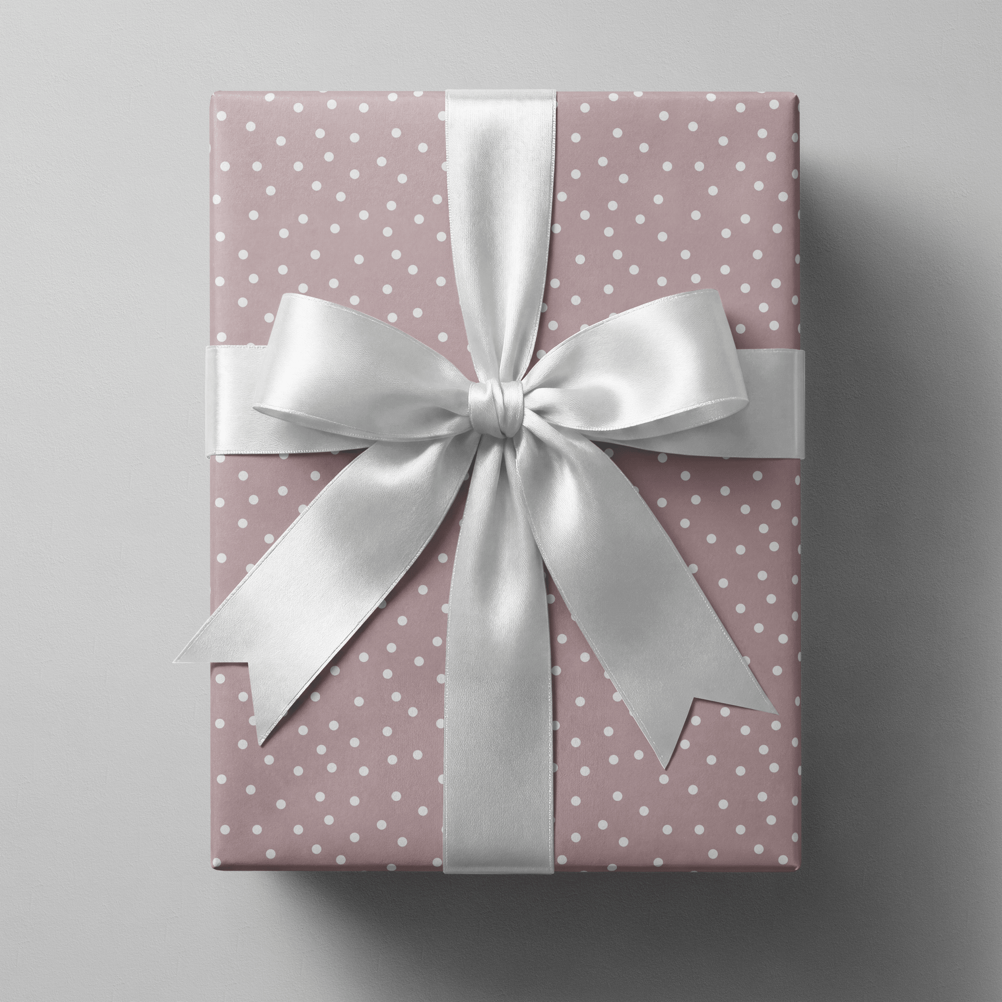 Polka dot wrapping paper pink with scattered white dots on a dusty mauve ground.