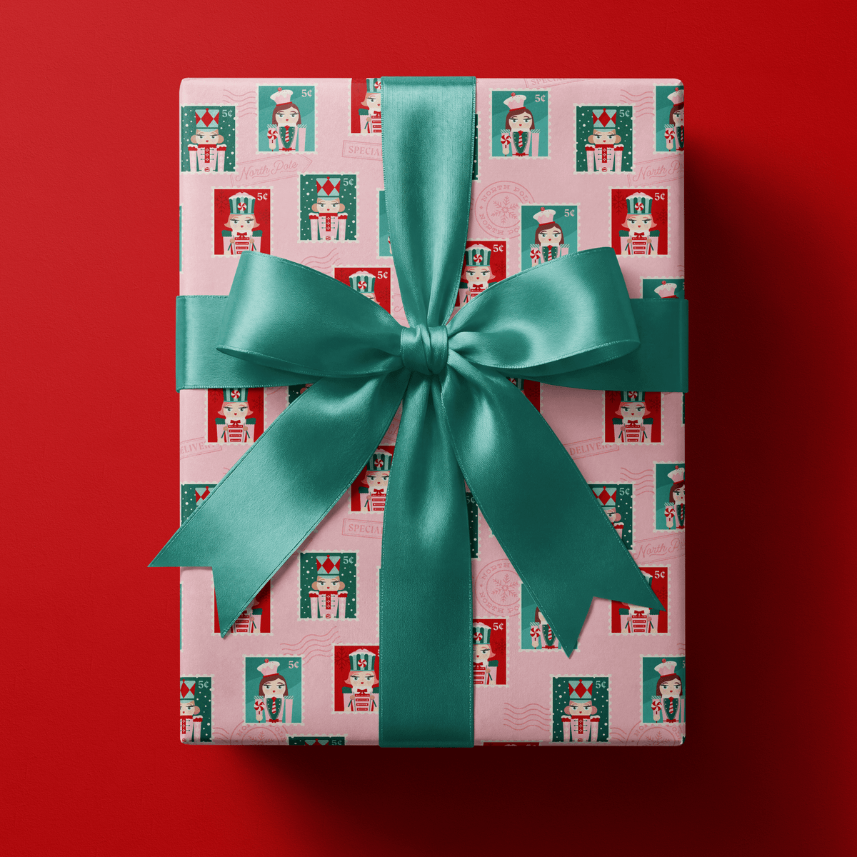 Pink nutcracker wrapping paper with girl nutcrackers in teal and red uniforms on pink.