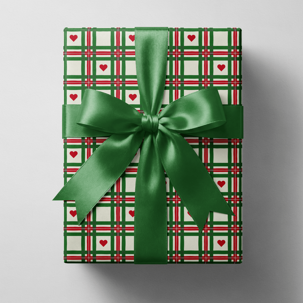 Plaid christmas wrapping paper with hand-drawn green and red lines and small red hearts.