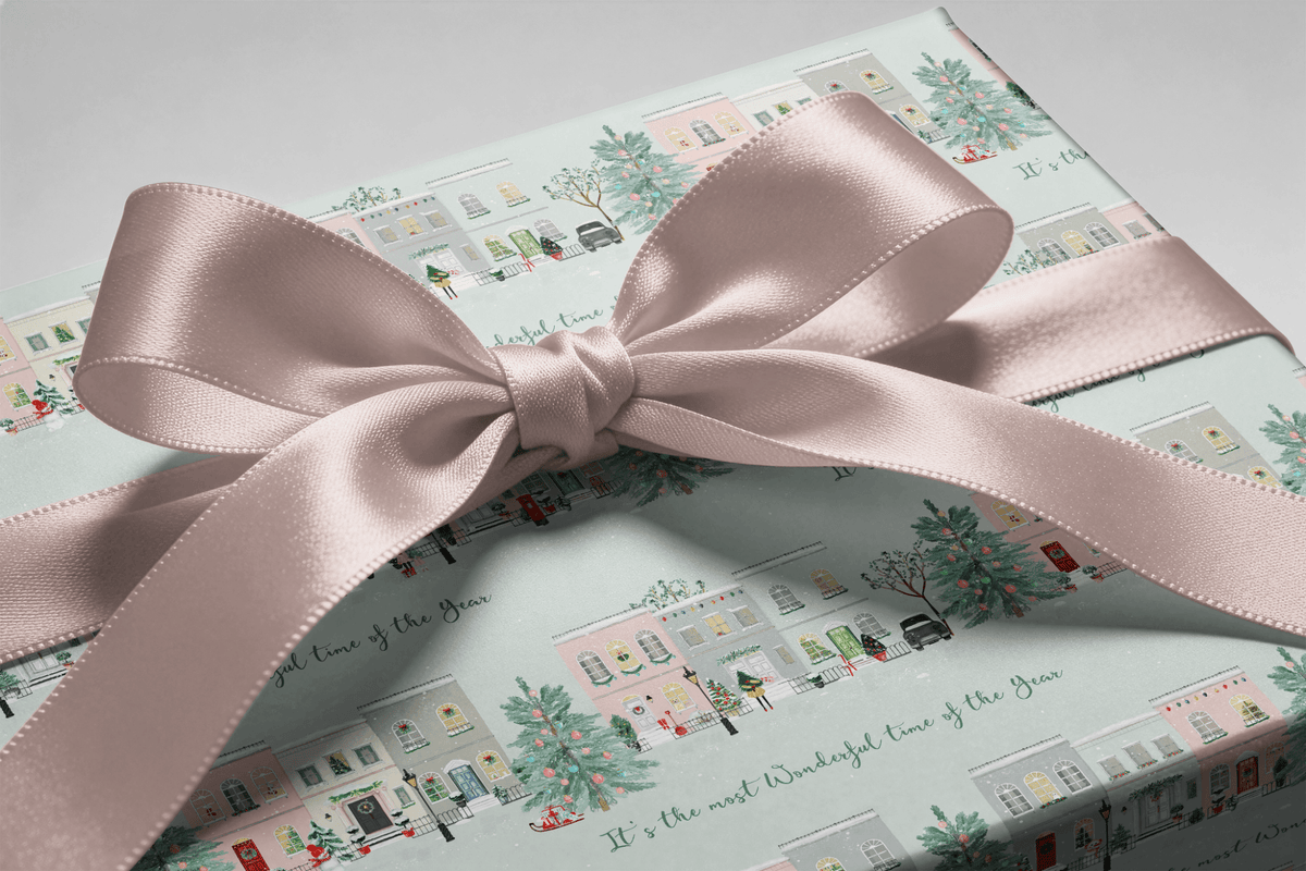 Flat lay showing the repeating pastel townhouse, tree, and light pattern on this wrapping paper