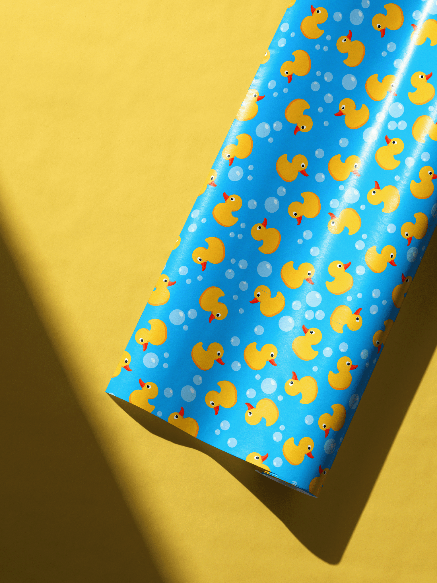 Vibrant blue rubber duck gift wrap featuring yellow ducks and bubbles for baby showers and nursery gifts.