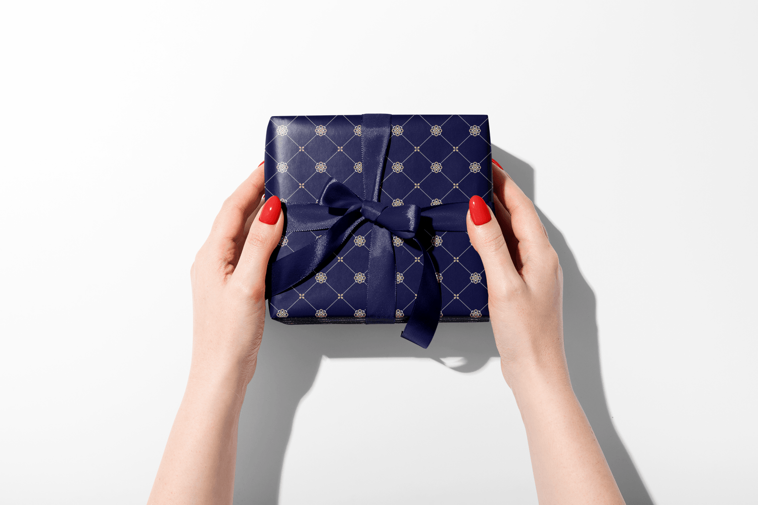 Blue gift box with a bow held by hands on a white background