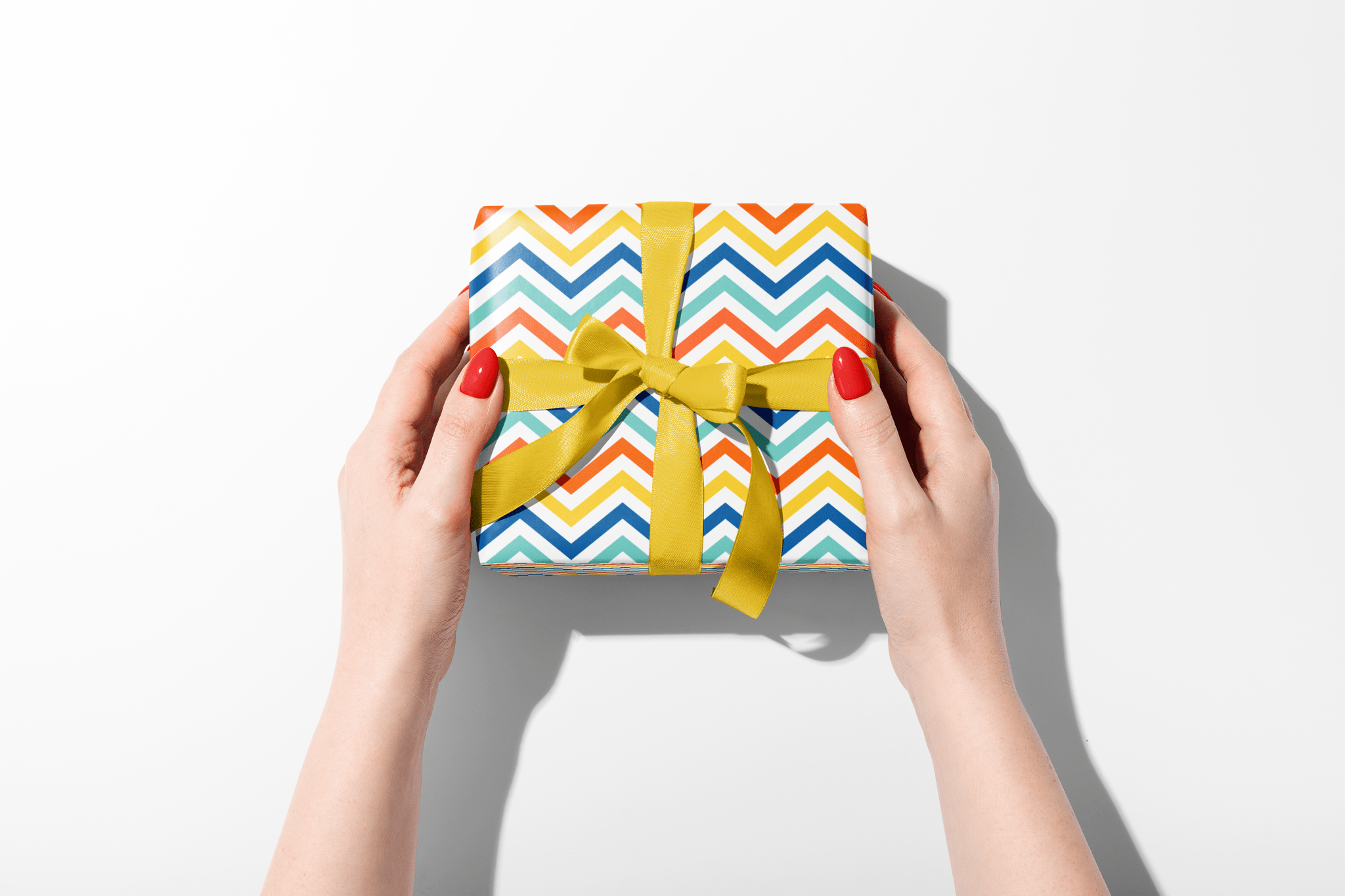 Colorful gift box with a yellow ribbon held by hands on a white background