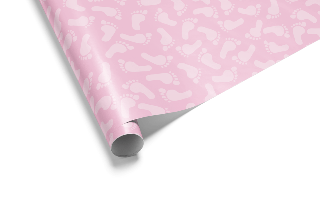 Solid light pink wrapping paper with a dense, subtle tone-on-tone pattern of tiny baby footprints, ideal for baby girl wrapping paper and baby shower gifts.