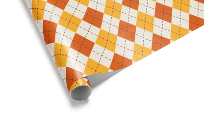 Cream-colored wrapping paper with a uniform Argyle pattern of alternating orange and yellow diamonds, ideal for fall wrapping paper and geometric wrapping paper.
