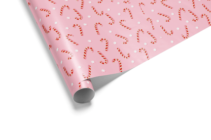 Light pink Christmas wrapping paper with a dense, scattered pattern of red and white striped candy canes and small white dots, ideal for cute Christmas wrapping paper.