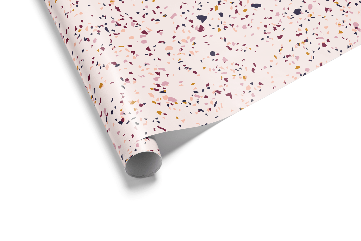 Blush pink wrapping paper with a dense, abstract terrazzo pattern featuring scattered flecks in burgundy, navy, and peach tones, ideal for modern, feminine gifts.