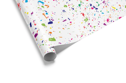 White wrapping paper covered in a dense, scattered pattern of tiny paint splatters in red, blue, green, yellow, and other rainbow colors.