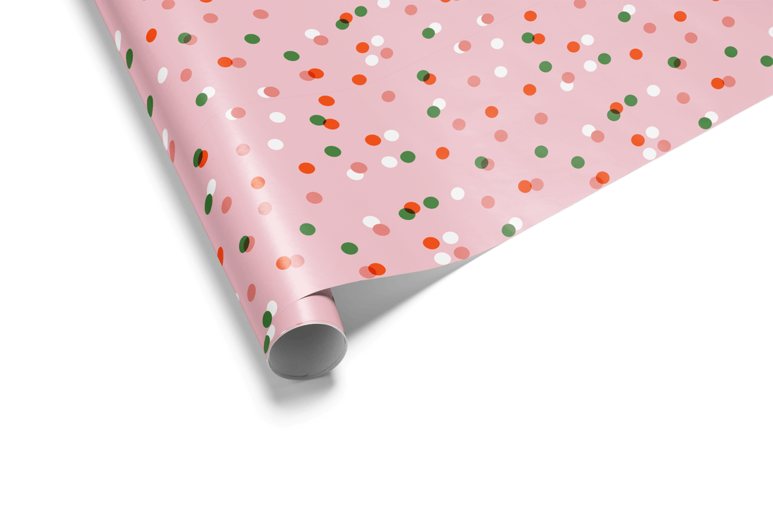 Pink Christmas wrapping paper with red, green, and white polka dots for holiday gifts.