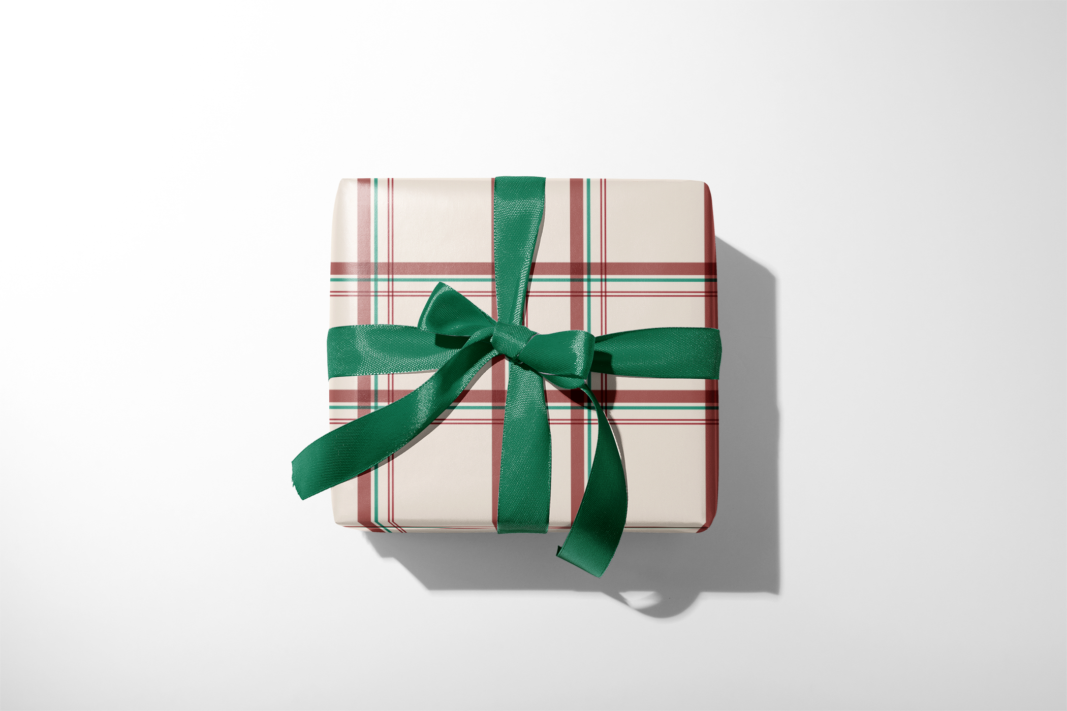 Alt Tag: Christmas Plaid Wrapping Paper in tartan registry pattern, cream base with red and green plaid lines, wrapped gift with green ribbon