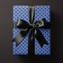 Alt Tag: Blue Polka Dot Wrapping Paper on gift box with black satin ribbon bow, modern minimalist midnight prep presentation