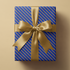Alt Tag: Blue and Gold Wrapping Paper with diagonal gold stripes on royal blue gift box, finished with a satin gold ribbon bow