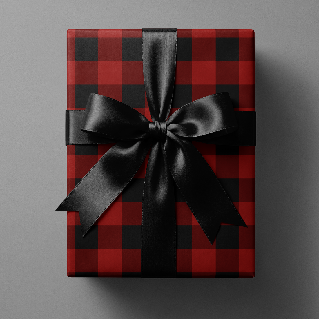 Buffalo Plaid Wrapping Paper in red and black tartan grid gift wrap with black satin ribbon bow, winter lodge holiday present