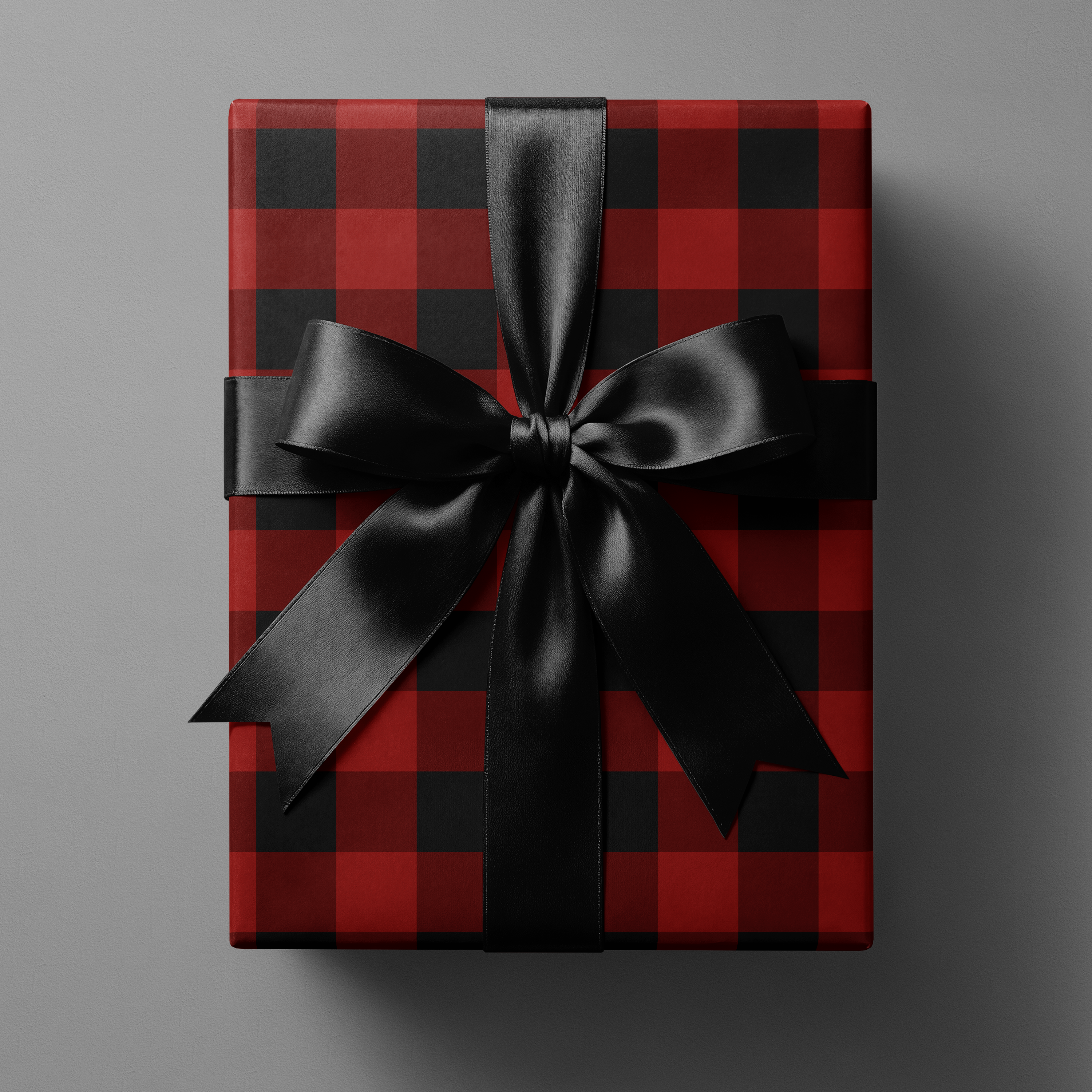 Buffalo Plaid Wrapping Paper in red and black tartan grid gift wrap with black satin ribbon bow, winter lodge holiday present