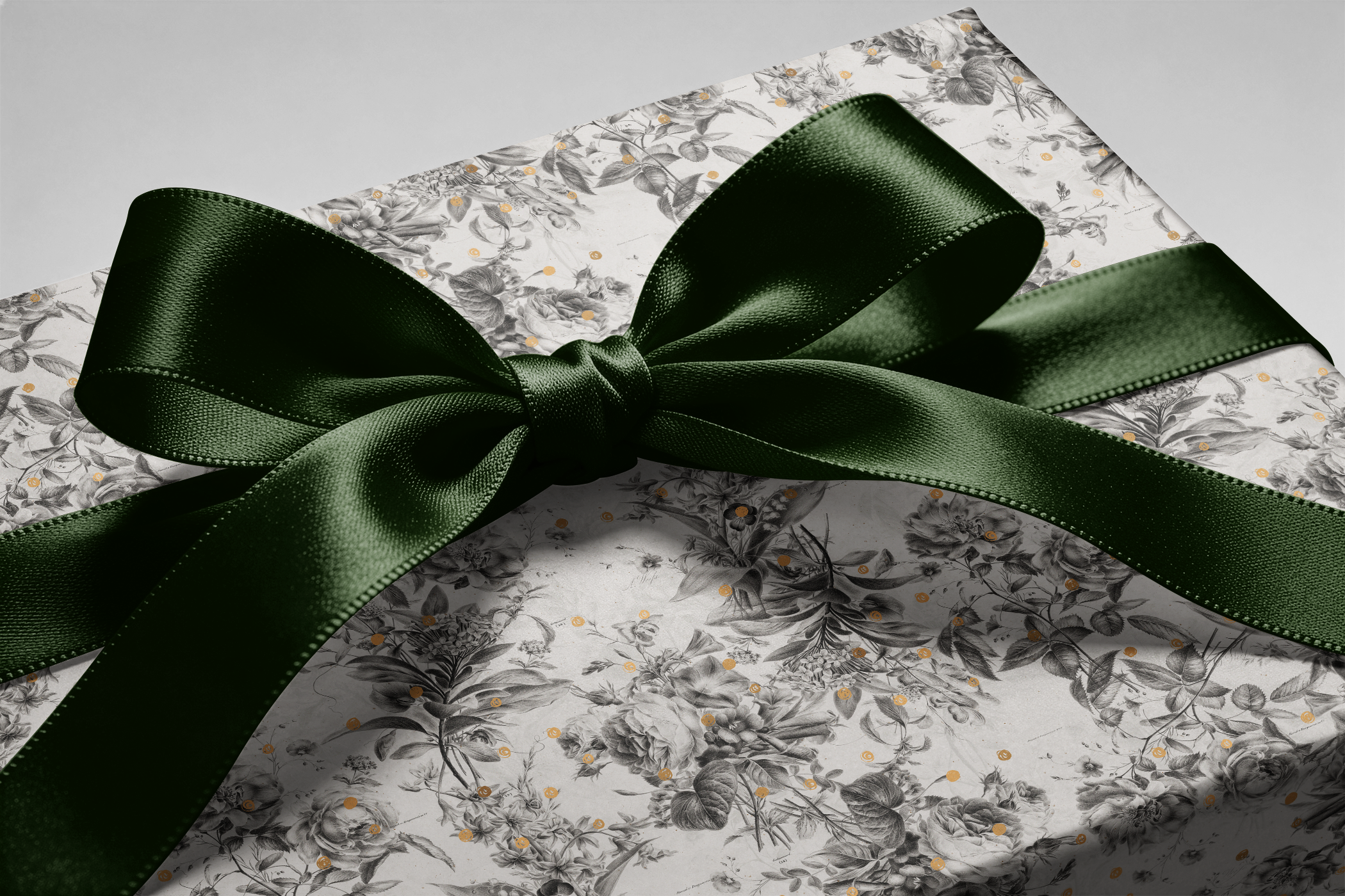 Alt Tag: Black and White Floral Wrapping Paper with botanical sketches and gold speckles, wrapped gift box with dark green satin bow