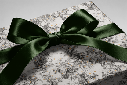 Alt Tag: Black and White Floral Wrapping Paper with botanical sketches and gold speckles, wrapped gift box with dark green satin bow