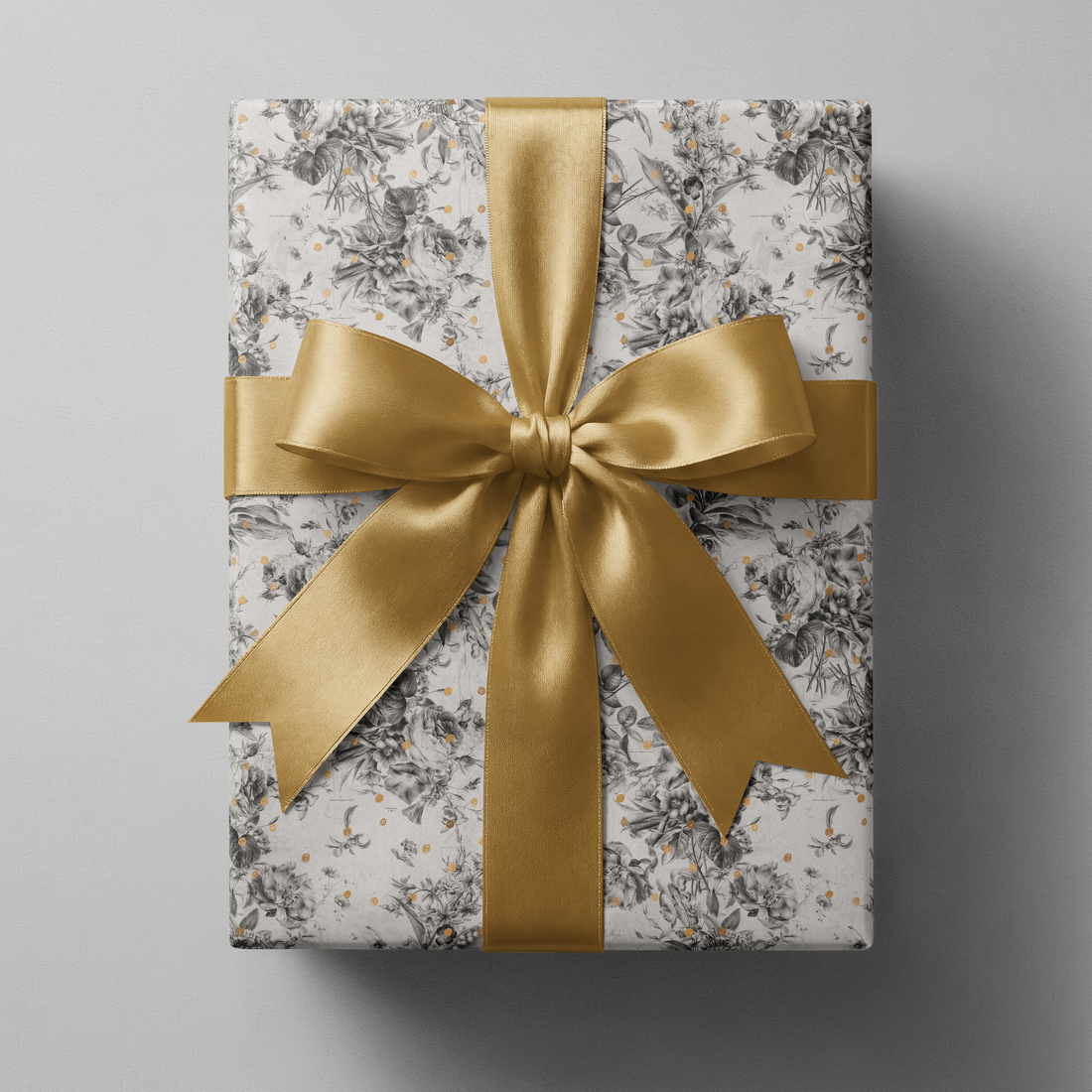 Alt Tag: Black and White Floral Wrapping Paper with botanical sketches and gold speckles, wrapped gift with gold satin ribbon bow