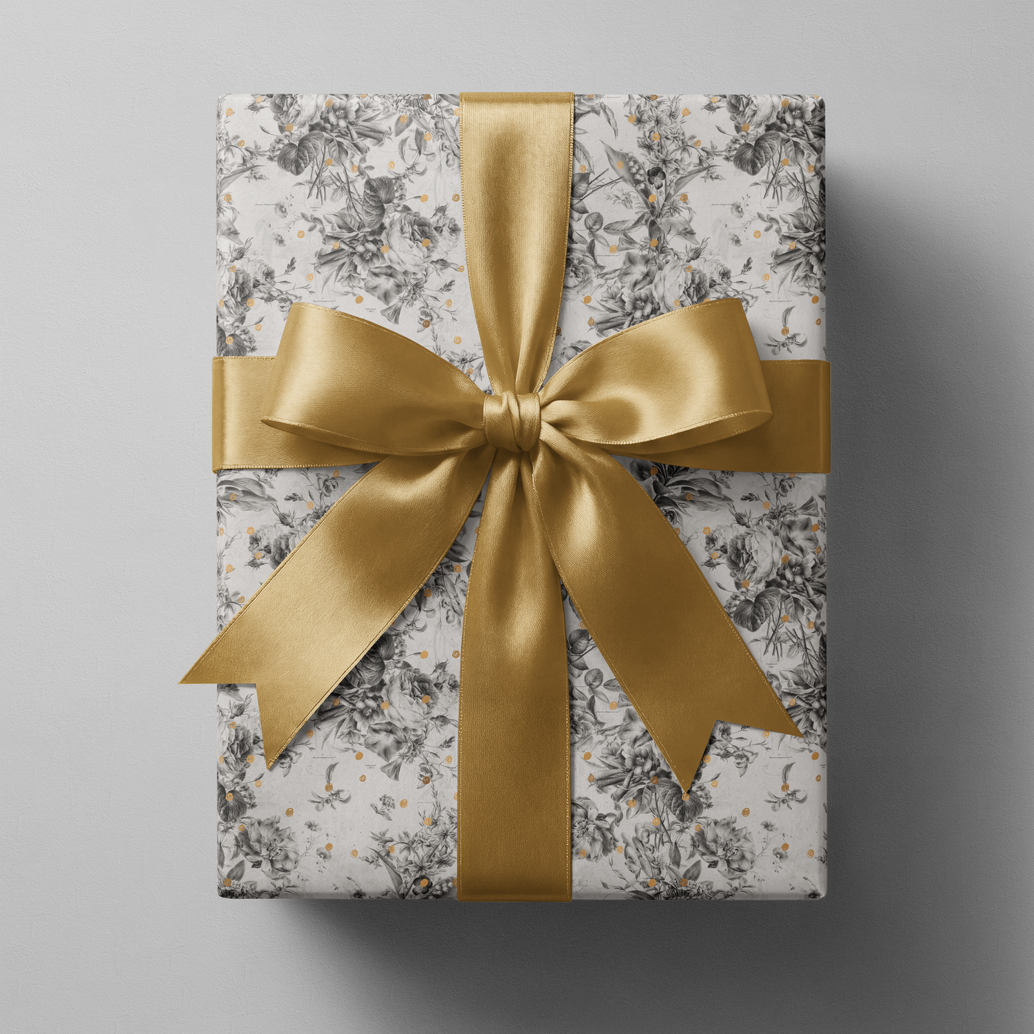 Alt Tag: Black and White Floral Wrapping Paper with botanical sketches and gold speckles, wrapped gift with gold satin ribbon bow