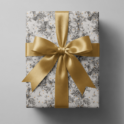 Alt Tag: Black and White Floral Wrapping Paper with botanical sketches and gold speckles, wrapped gift with gold satin ribbon bow