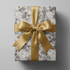 Alt Tag: Black and White Floral Wrapping Paper with botanical sketches and gold speckles, wrapped gift with gold satin ribbon bow