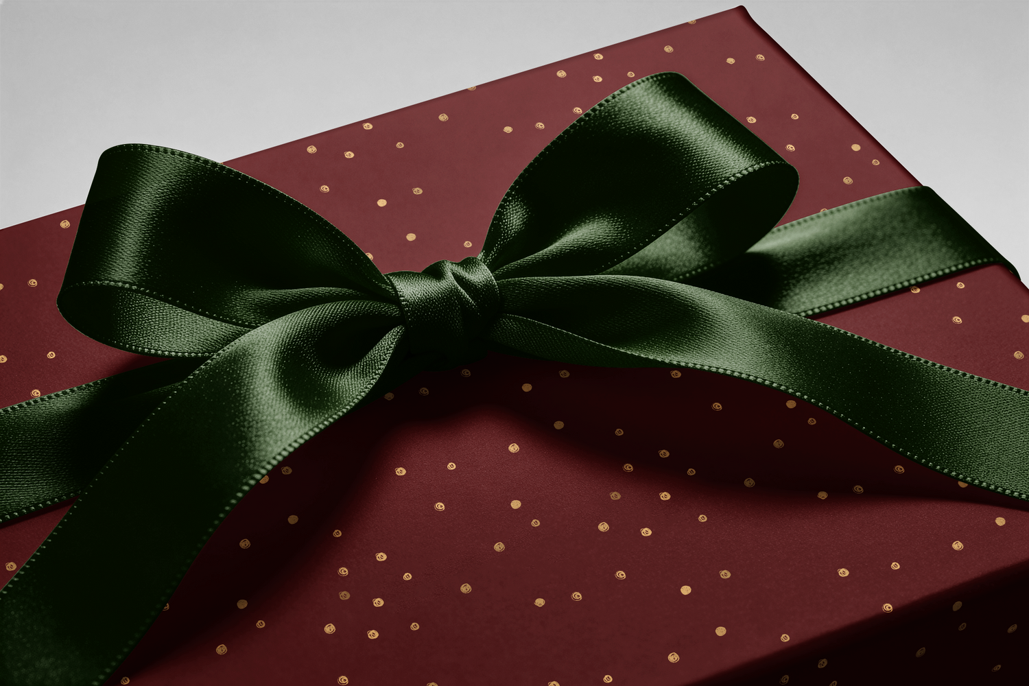 Alt Tag: Burgundy and Gold Wrapping Paper gift wrap with gold flecks and dark green satin ribbon bow on a present