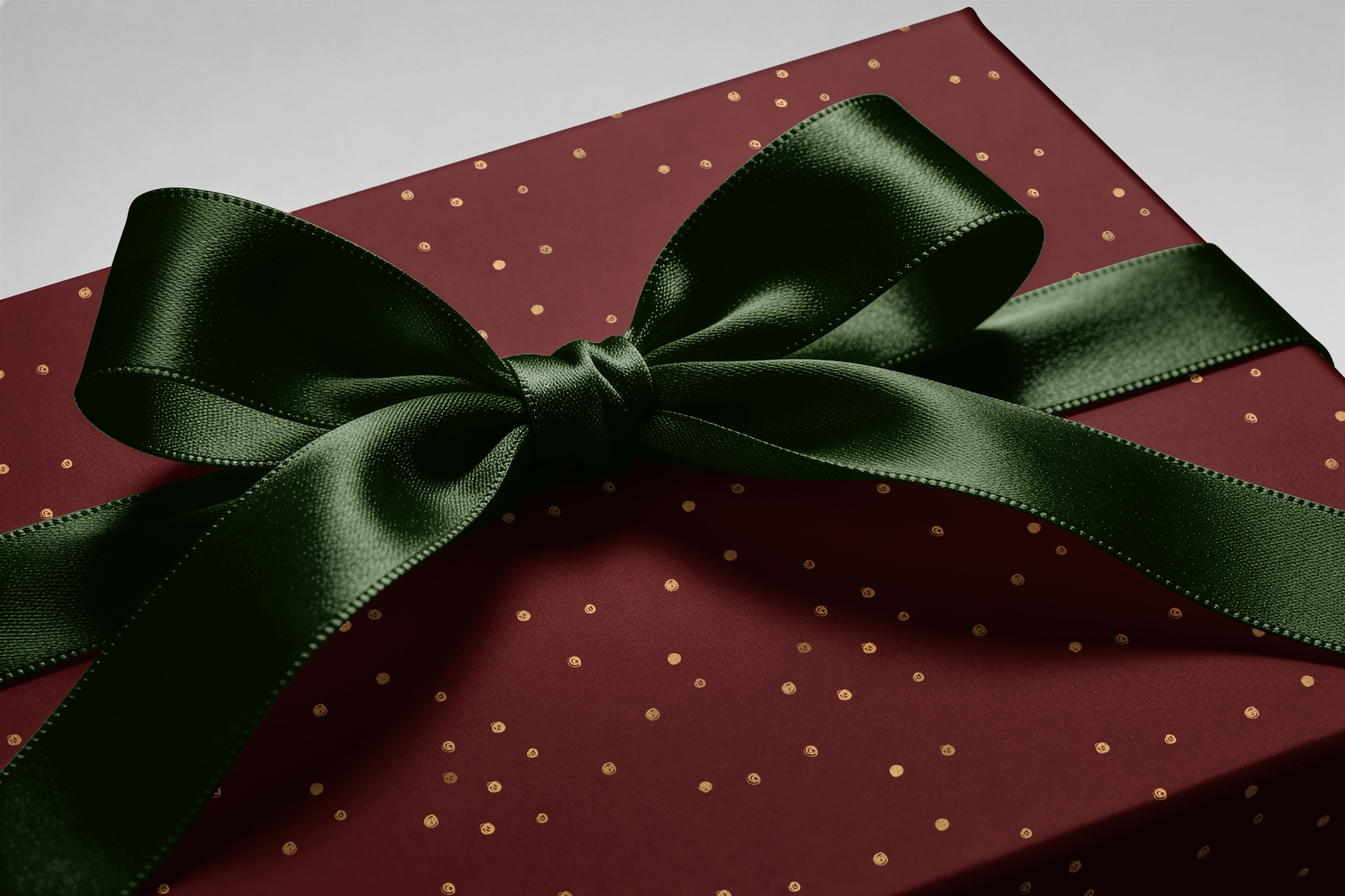 Alt Tag: Burgundy and Gold Wrapping Paper gift wrap with gold flecks and dark green satin ribbon bow on a present