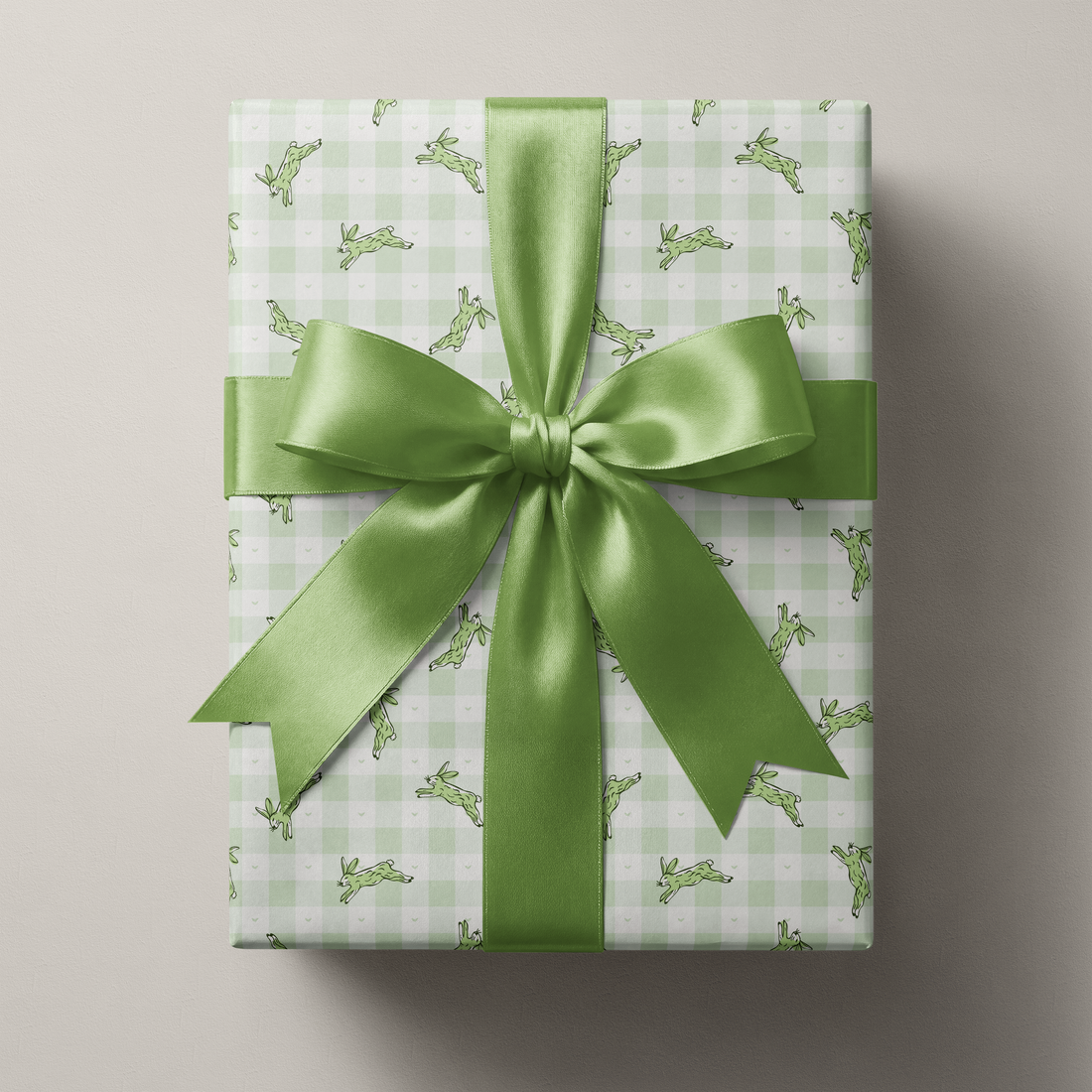 Alt Tag: Bunny Wrapping Paper with sage green gingham and running hare print, wrapped gift with green satin ribbon bow