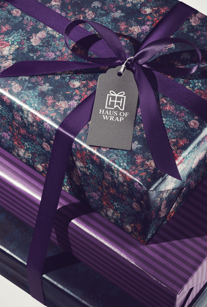 Alt Tag: Velvet Noir Moody Floral Christmas Wrapping Paper on gift box with dark jewel-toned florals, purple ribbon, and Haus of Wrap tag
