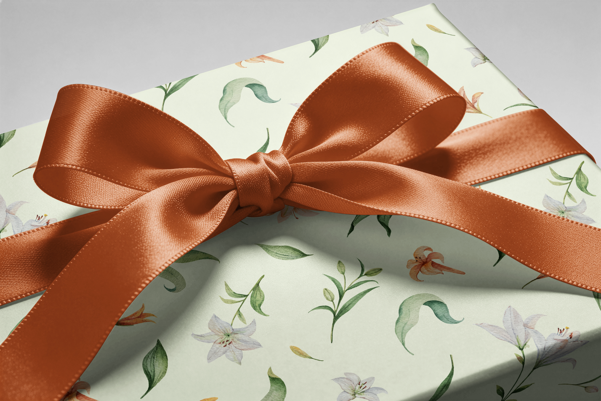Alt Tag: Floral Wrapping Paper on gift box with sage background, lilies and peach blossoms, finished with a copper satin ribbon bow