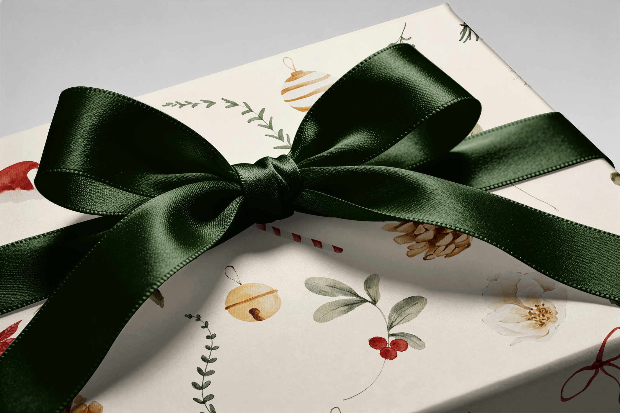 Alt Tag: Winter Garden botanical Christmas wrapping paper with watercolor pinecones, holly, ornaments on cream, wrapped gift with dark green satin bow
