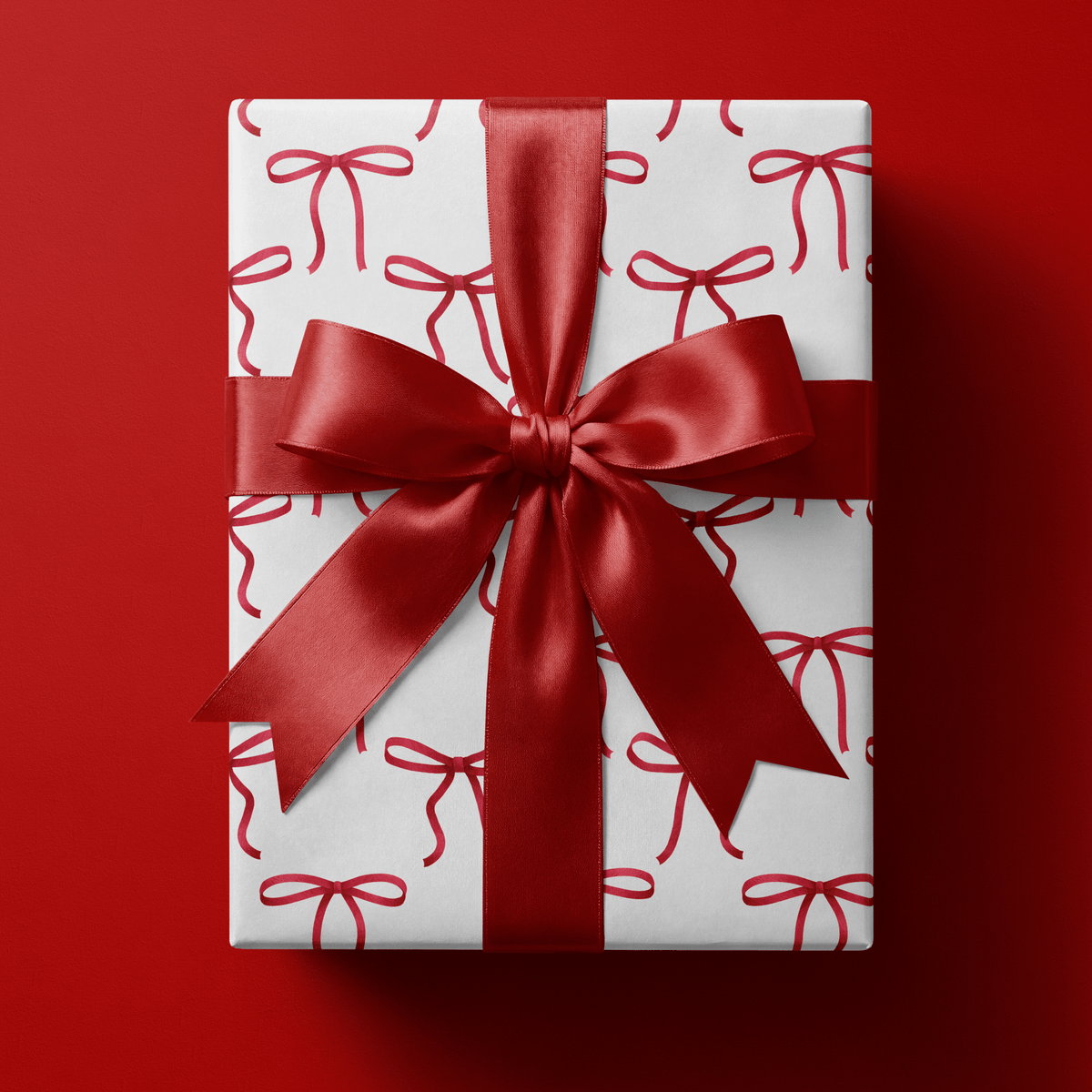 Coquette wrapping paper with hand-painted red bows and trailing tails scattered on white.
