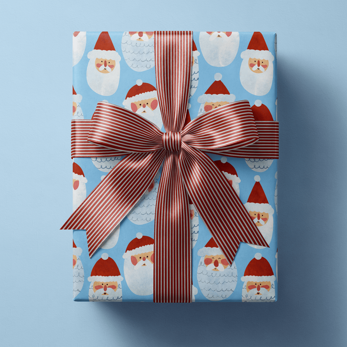 Santa Christmas wrapping paper with cheerful folk-drawn Santa faces in red hats on sky blue.
