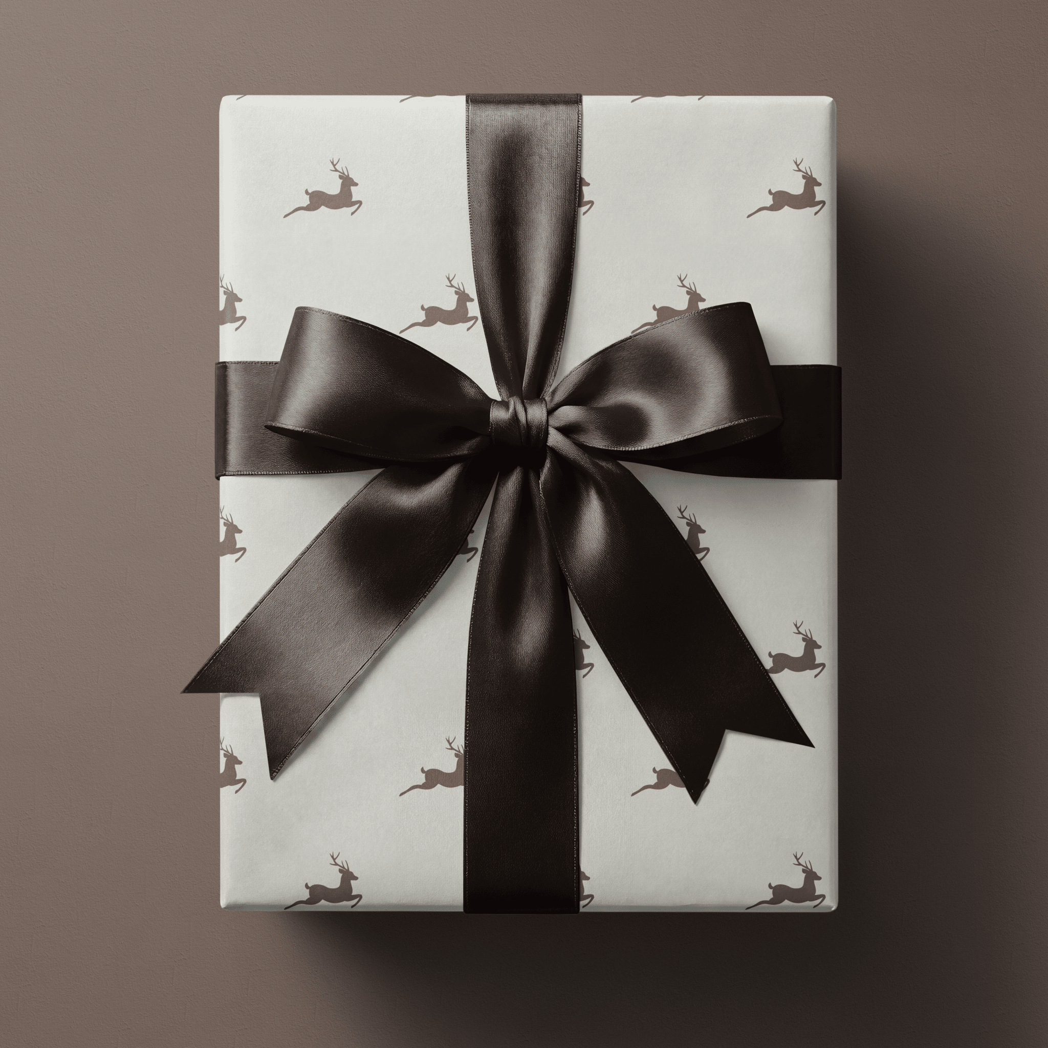 Neutral Christmas wrapping paper with leaping taupe stags spaced evenly across a cream ground.