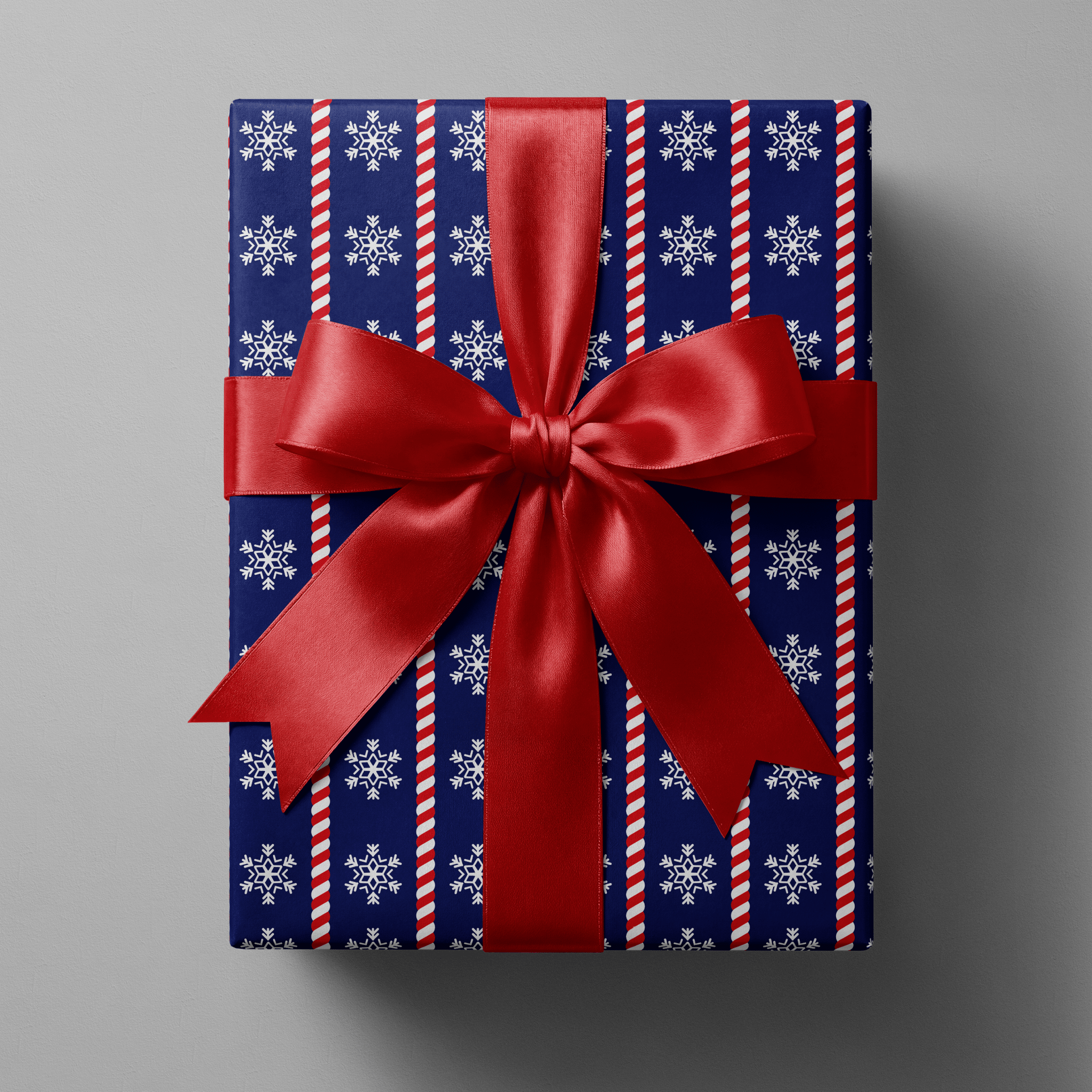 Navy Christmas wrapping paper with white snowflakes divided by red and white candy-cane twist stripes.
