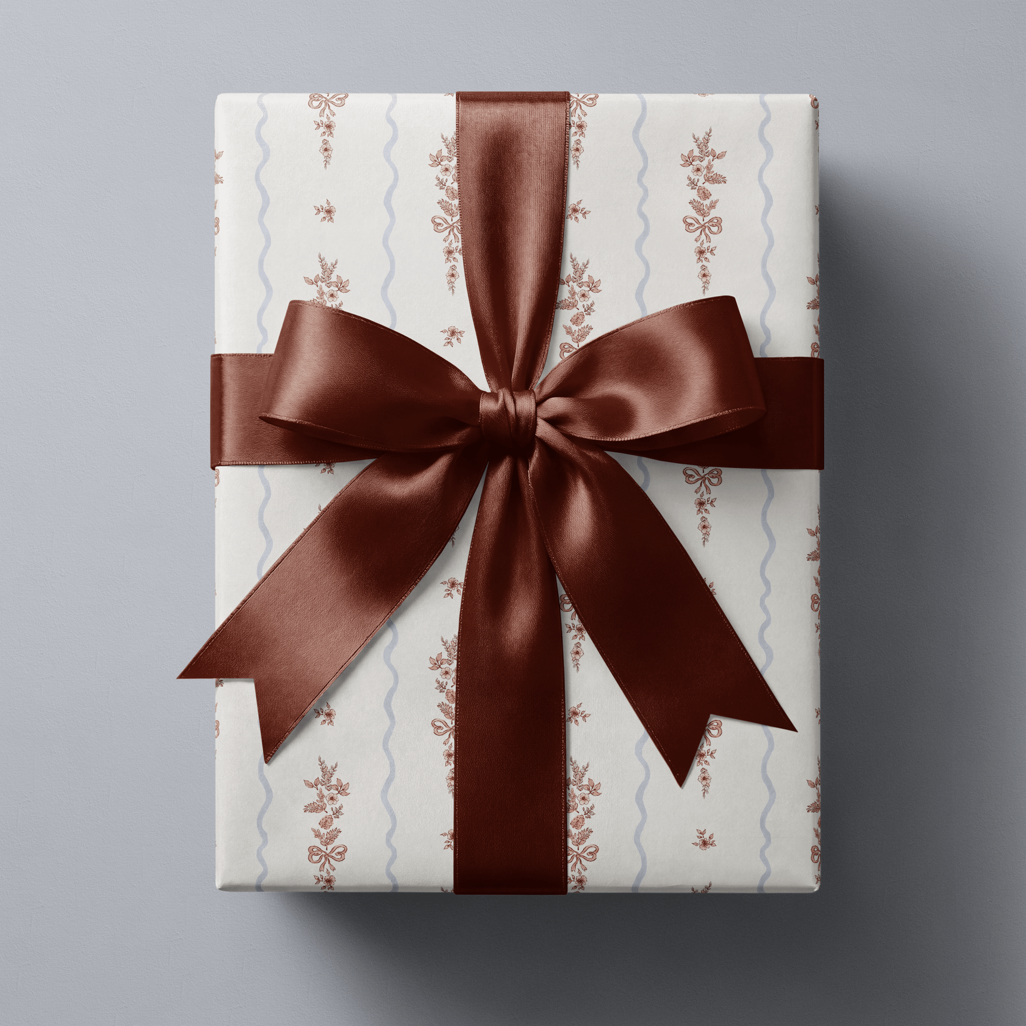 Floral Christmas wrapping paper with rose-pink botanical sprigs and little bows on white, divided by pale blue scallop stripes.