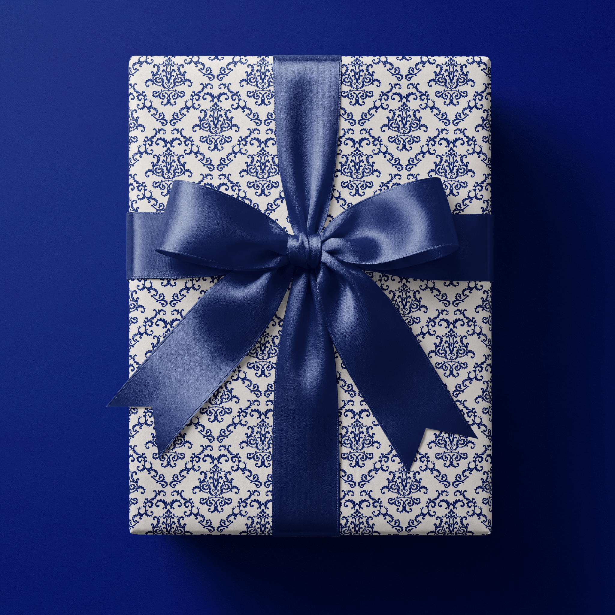 Elegant wedding wrapping paper with an intricate navy blue damask of scrolling filigree medallions on white, finished with a navy satin bow.
