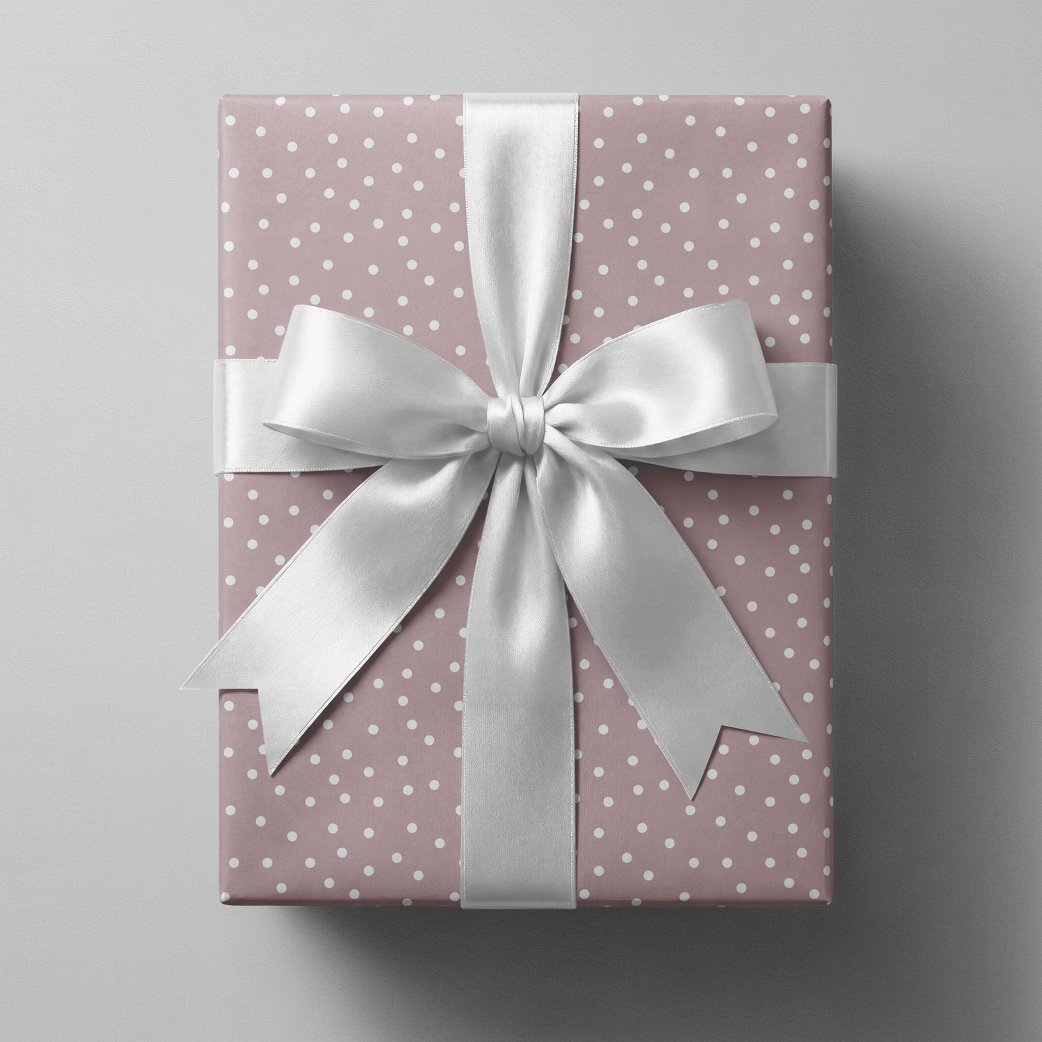 Polka dot wrapping paper pink with scattered white dots on a dusty mauve ground.