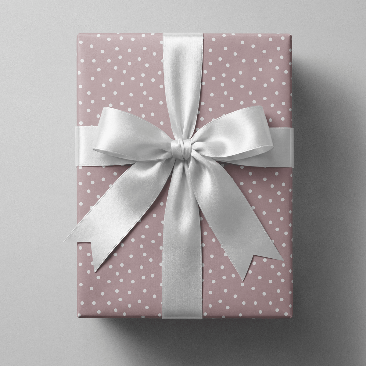 Polka dot wrapping paper pink with scattered white dots on a dusty mauve ground.
