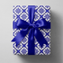 Blue and white christmas wrapping paper with a navy diamond lattice and snowflake medallions.